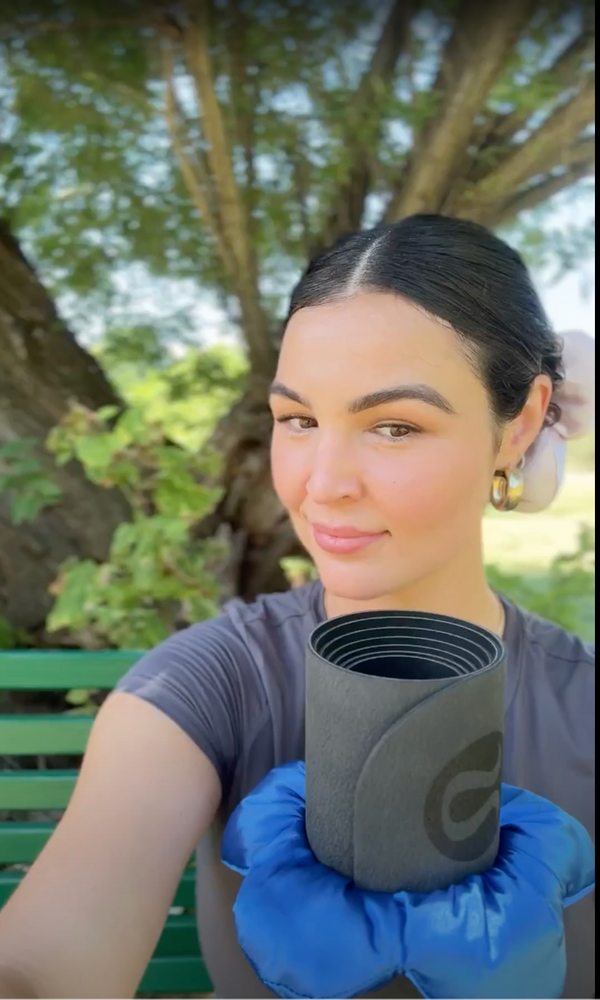 video of a woman in nature talking about her matbloom silk flower mat scrunchie that is secured around her black lululemon yoga mat. she has a pink silk flower scrunchie in her hair